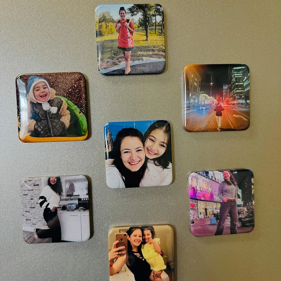 Custom photo fridge magnets attached to a steel refrigerator surface