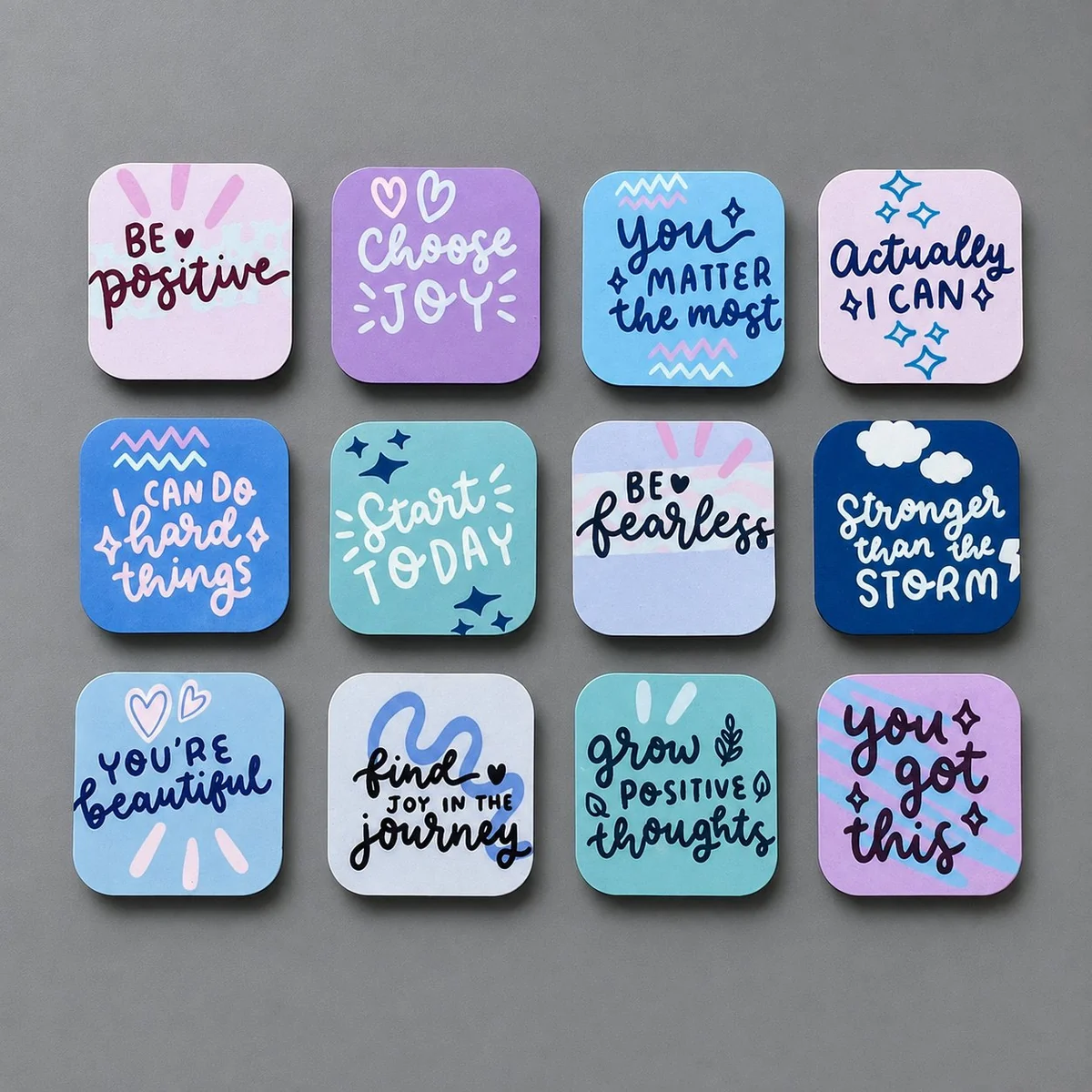 Twelve custom affirmation magnets with positive messages laid out on a table