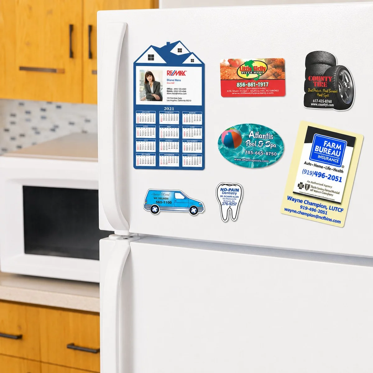 Real estate calendar fridge magnet alongside insurance and home service magnets on a refrigerator