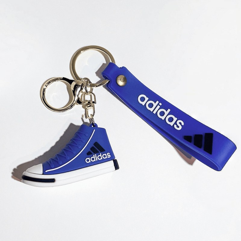 Adidas mini shoe keychain in blue, with a blue wrist strap printed with lettering and a gold-tone split ring