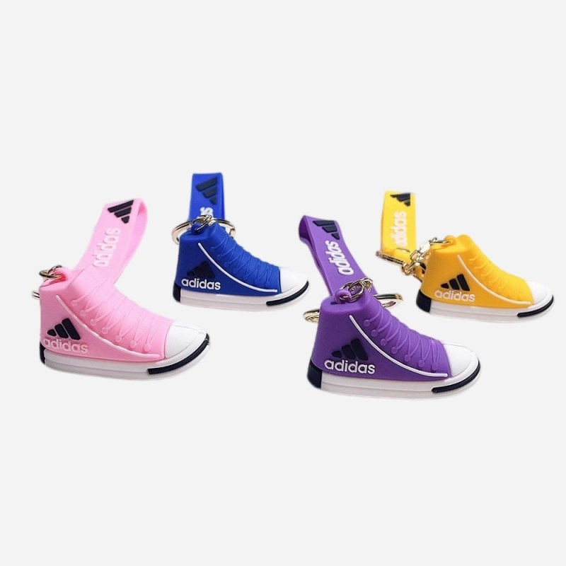 Adidas mini shoe keychains in pink, blue, purple and yellow arranged together, showing the high-top shape and wrist straps
