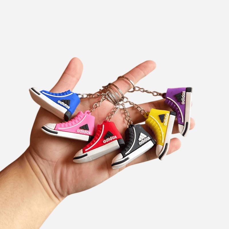 Adidas mini shoe keychains in six shades held in one hand, showing the full stock colour range and size in the palm