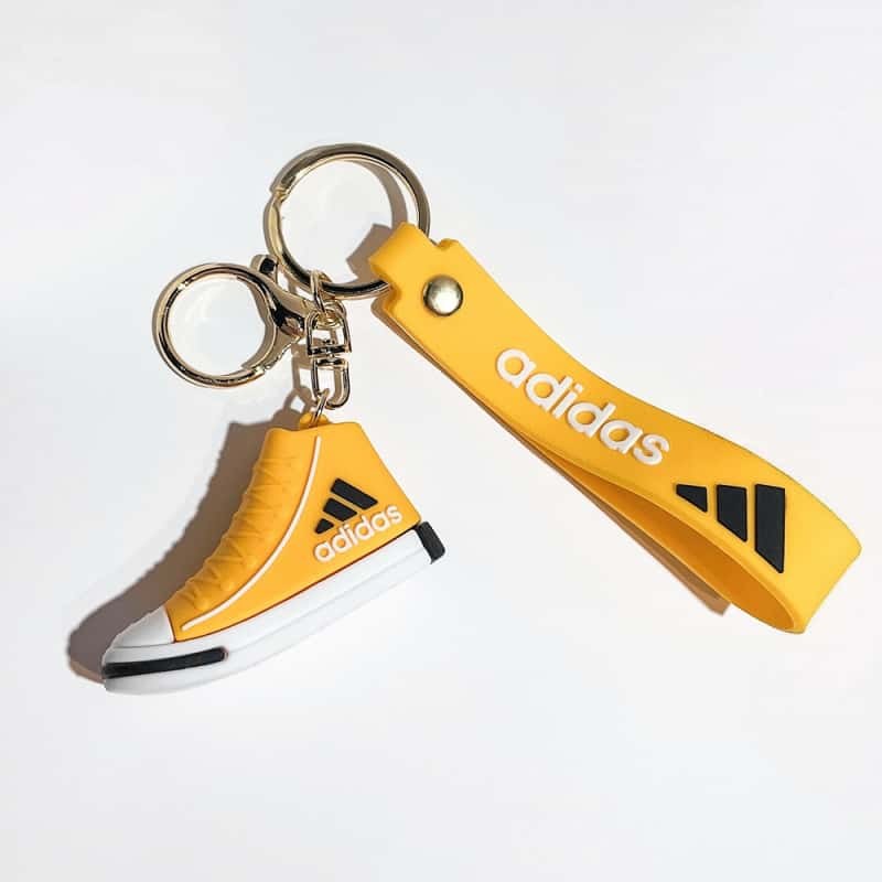 Adidas mini shoe keychain in yellow, with a yellow printed wrist strap and gold-tone hardware on a short chain