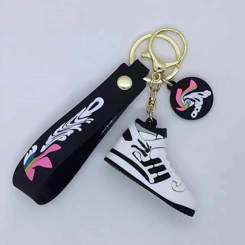 Adidas shoe key ring on a black printed tag strap with a black, white and pink mini sneaker