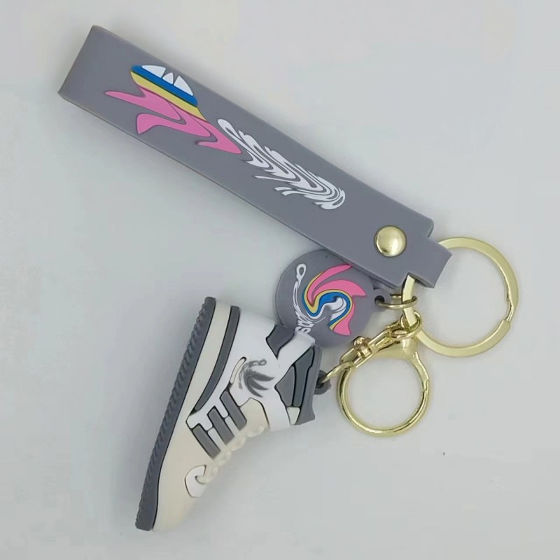 Adidas shoe keychain on a grey printed tag strap, with a white and grey mini sneaker on a gold-tone ring