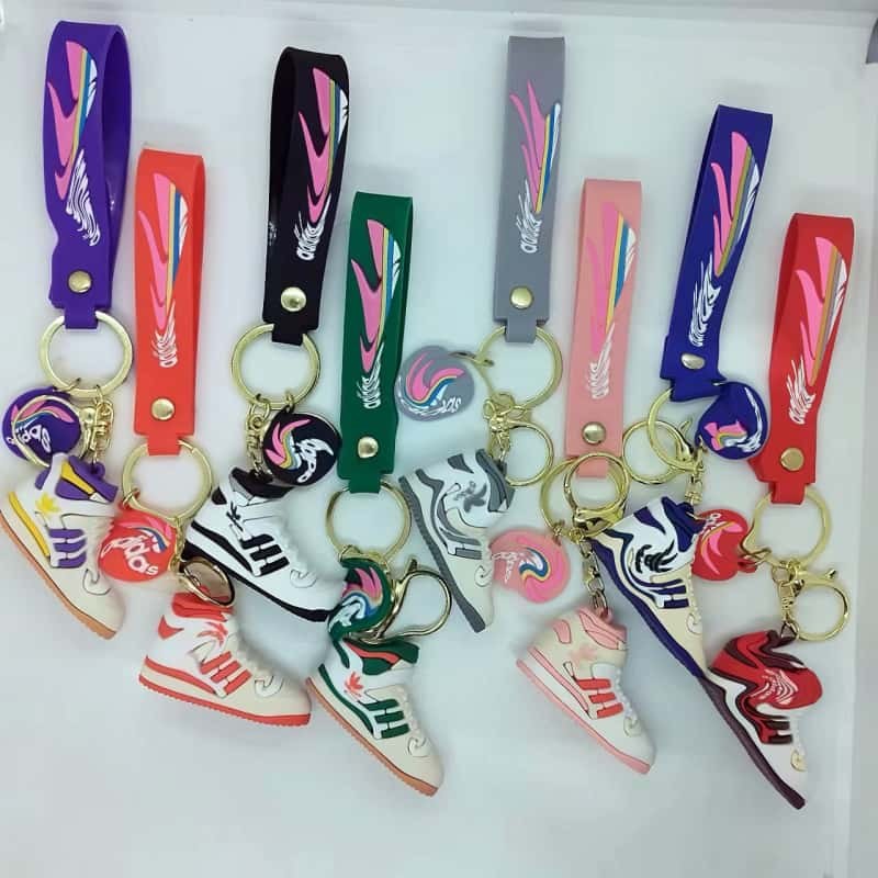 Adidas shoe keychains in a row of stock shades, each mini sneaker hung from a matching printed tag strap