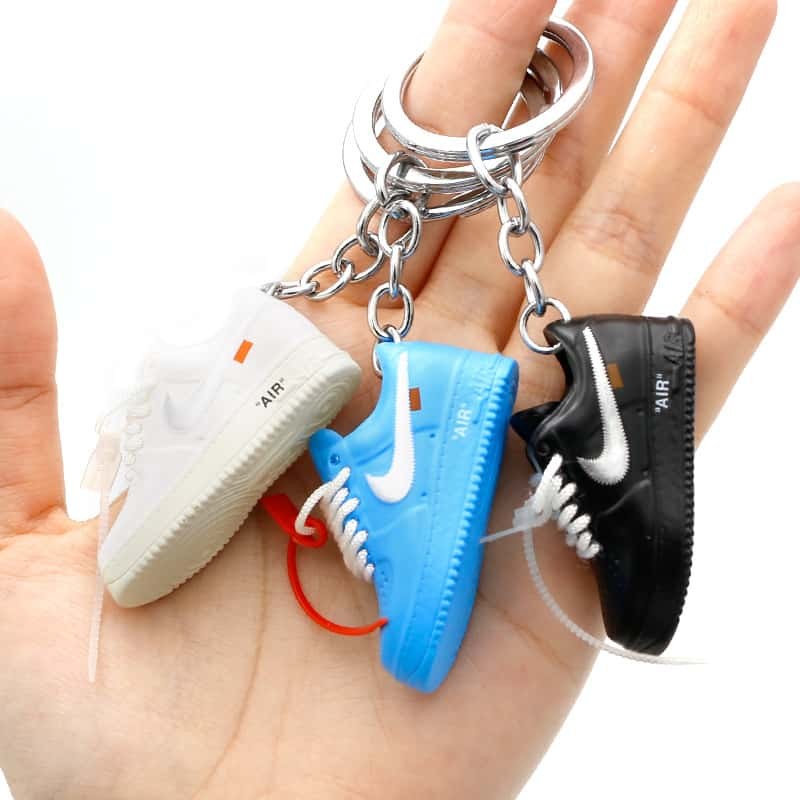 Air Force One shoe keychains in three colourways held in one hand, showing how the 5.2 cm piece sits against the palm