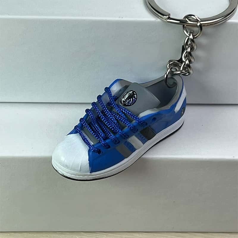 Basketball shoe keychain in blue and grey hanging on its chain, showing the moulded side stripes and sole