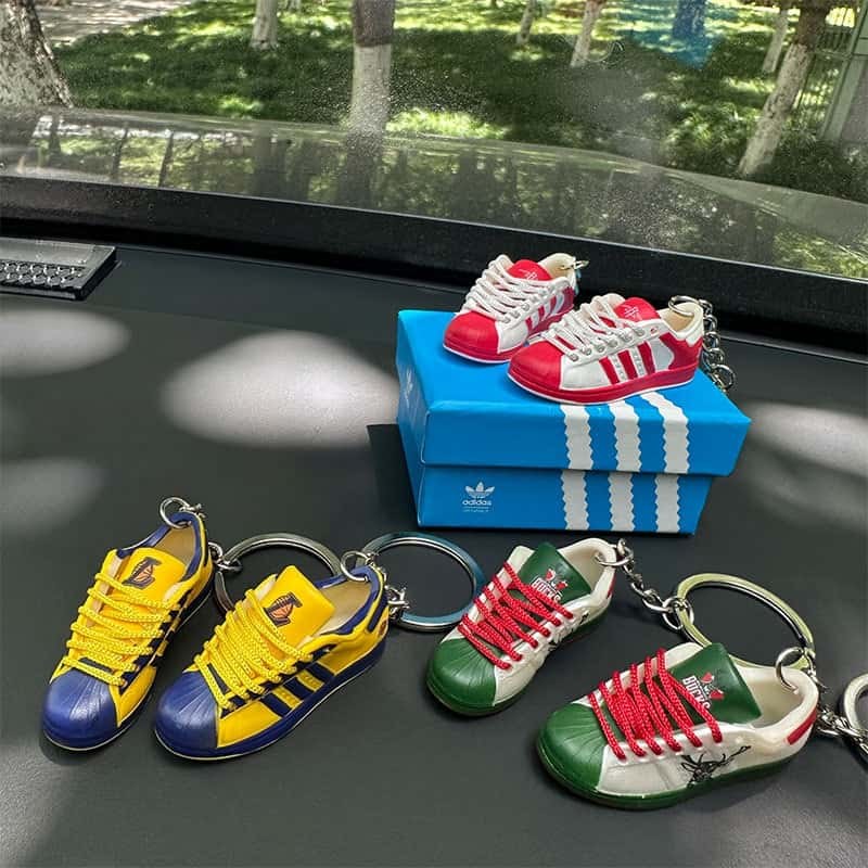 A red and white pair of basketball shoe keychains balanced on a blue printed gift box lid