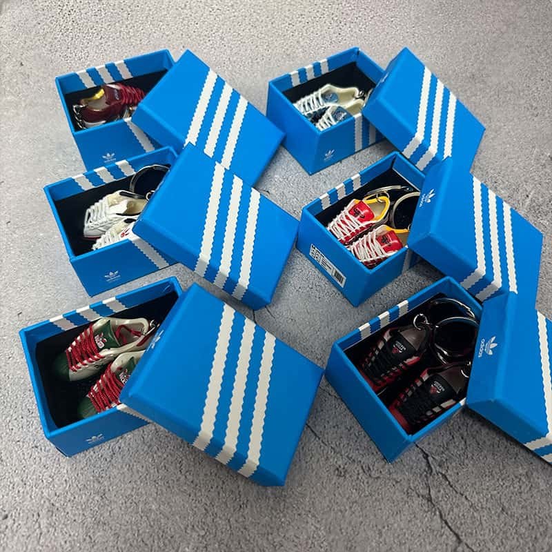 Basketball shoe keychains packed two to a printed gift box, boxes laid out as a group on a concrete floor