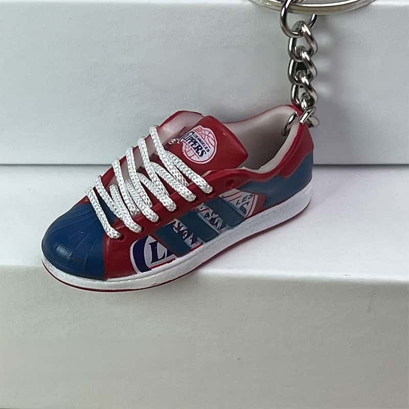 Basketball shoe keychain in red and blue shown side on, with white laces and a printed heel mark