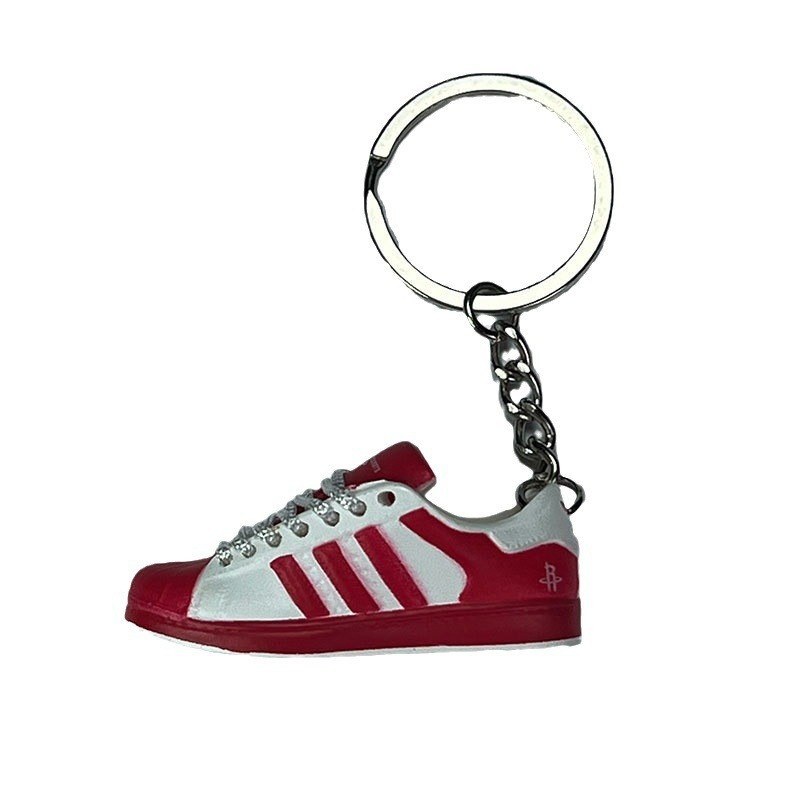 Basketball shoe keychain in red and white, seen from the side with the laces and shell toe picked out