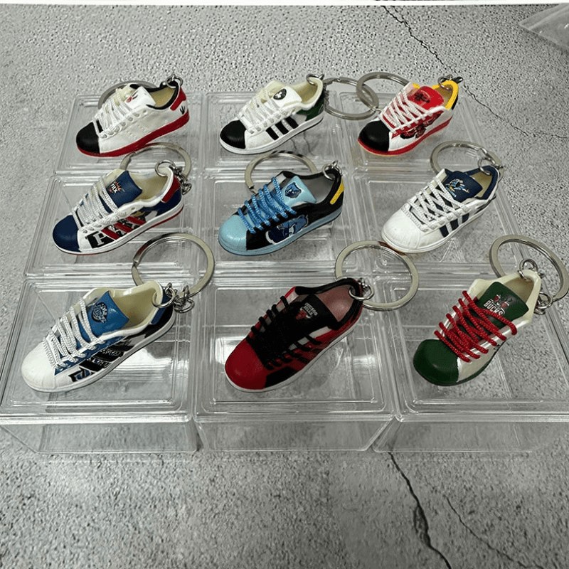 Twelve basketball shoe keychains in mixed team colourways resting on clear acrylic display trays