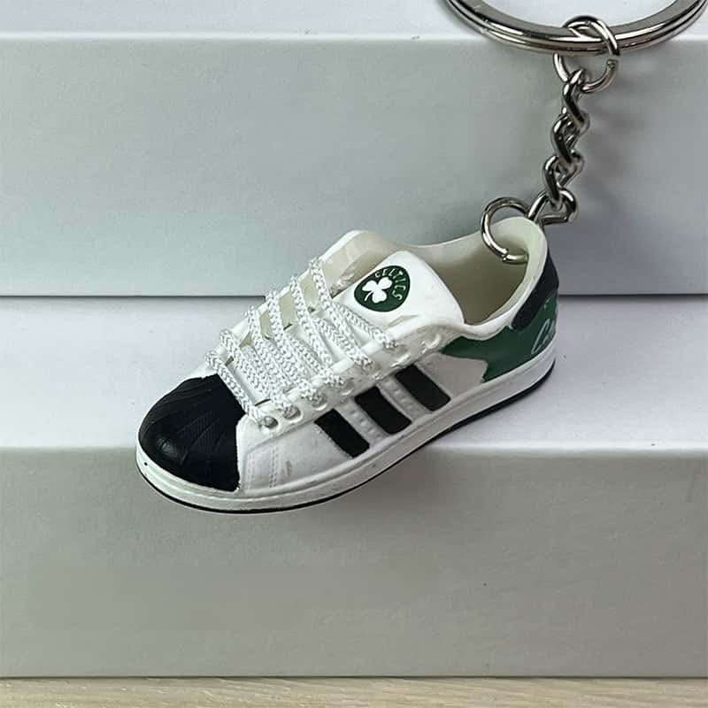 Basketball shoe keychain in white, black and green with a printed emblem on the tongue