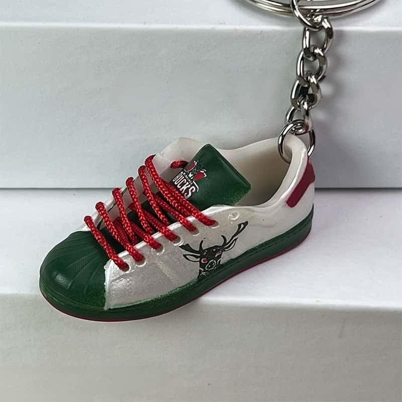 Basketball shoe keychain in white, green and red with red laces, shown against a white step