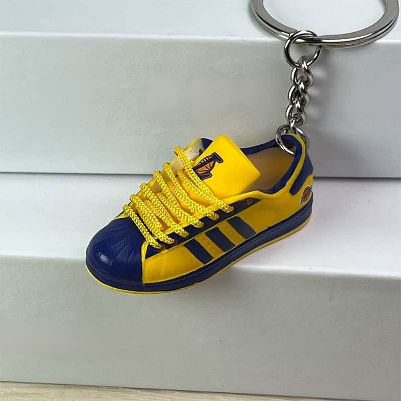 Basketball shoe keychain in yellow and blue with yellow laces, hanging from a silver-tone split ring