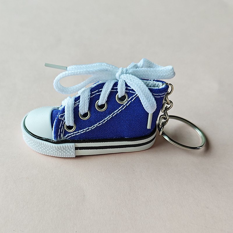 Blue mini canvas shoe keychain with white laces, eyelets and a short chain