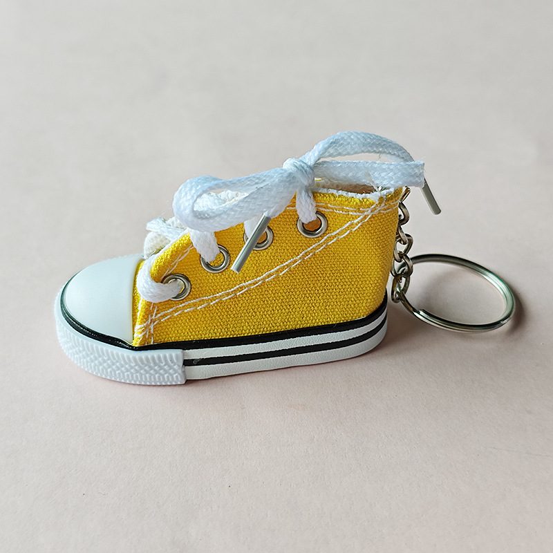 Yellow mini canvas shoe keychain with white laces and a silver key ring