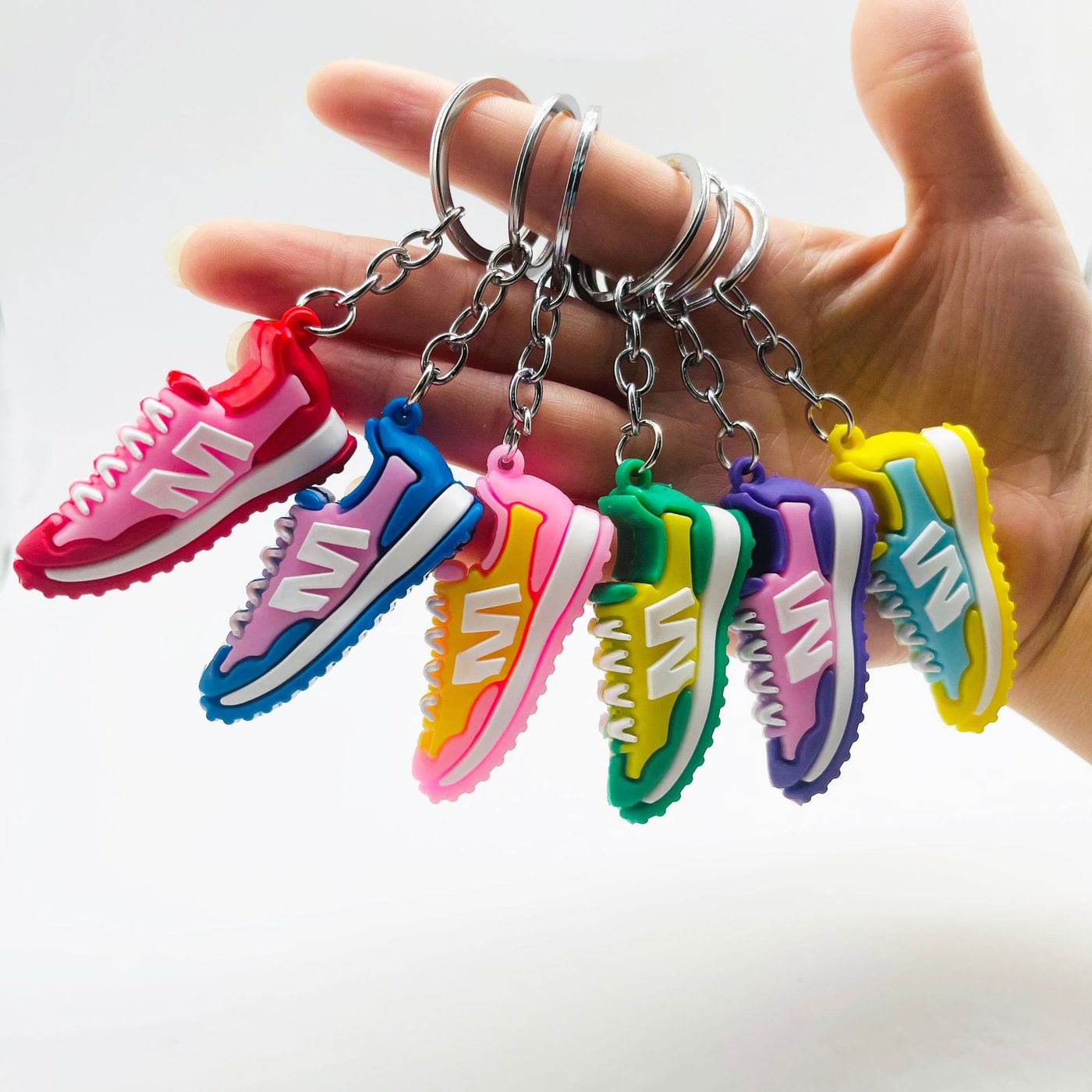 Six PVC sneaker keychains held in one hand, one of every stock two-tone colorway