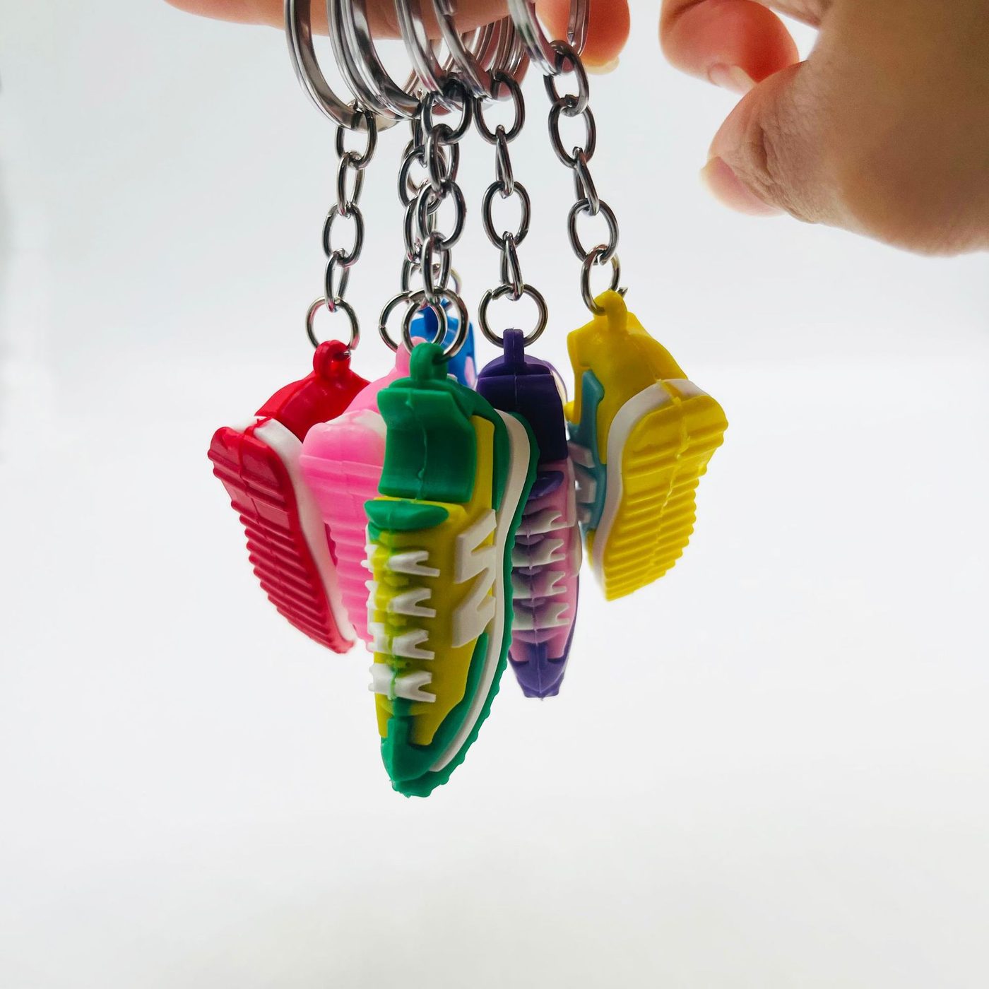 PVC sneaker keychains hung in a row showing the soles before packing