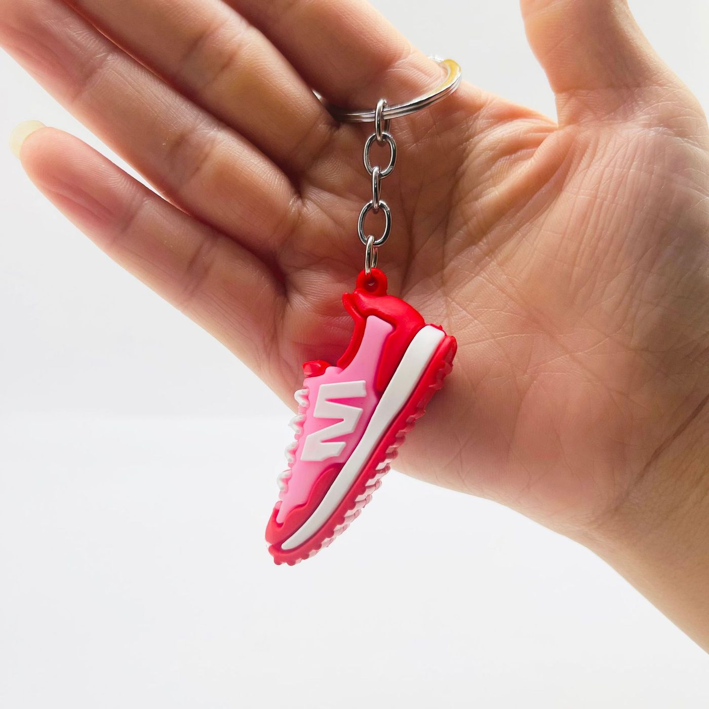 Red and pink PVC sneaker keychain showing the molded sole and tread, held in a hand