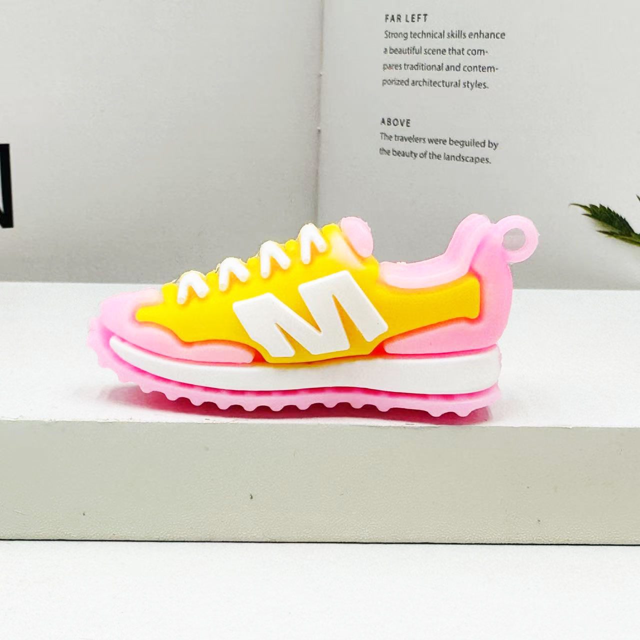 Yellow and pink PVC sneaker keychain in side profile on a white display block