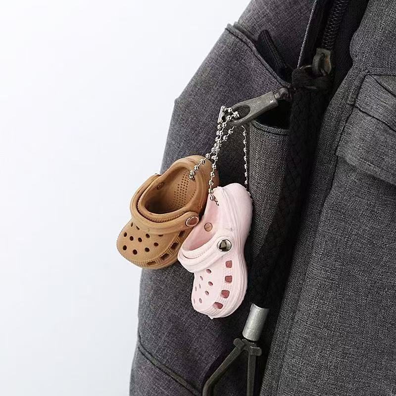 Custom realistic clog keychains clipped onto a bag zipper, in use as bag charms