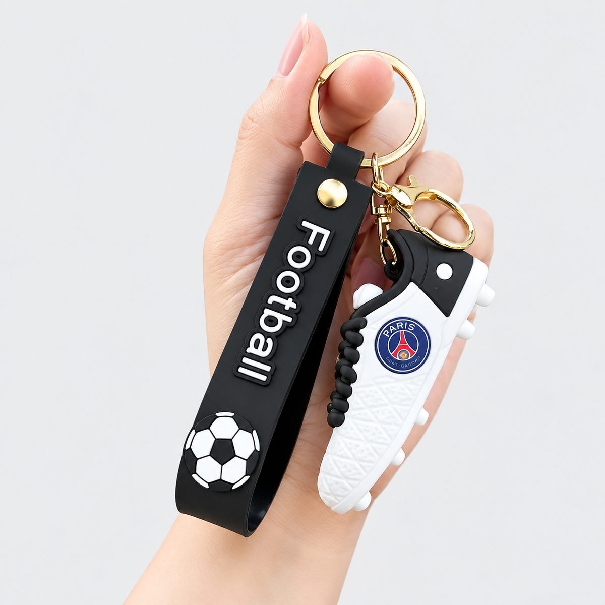 Realistic football shoe keychain with football-print strap held in hand