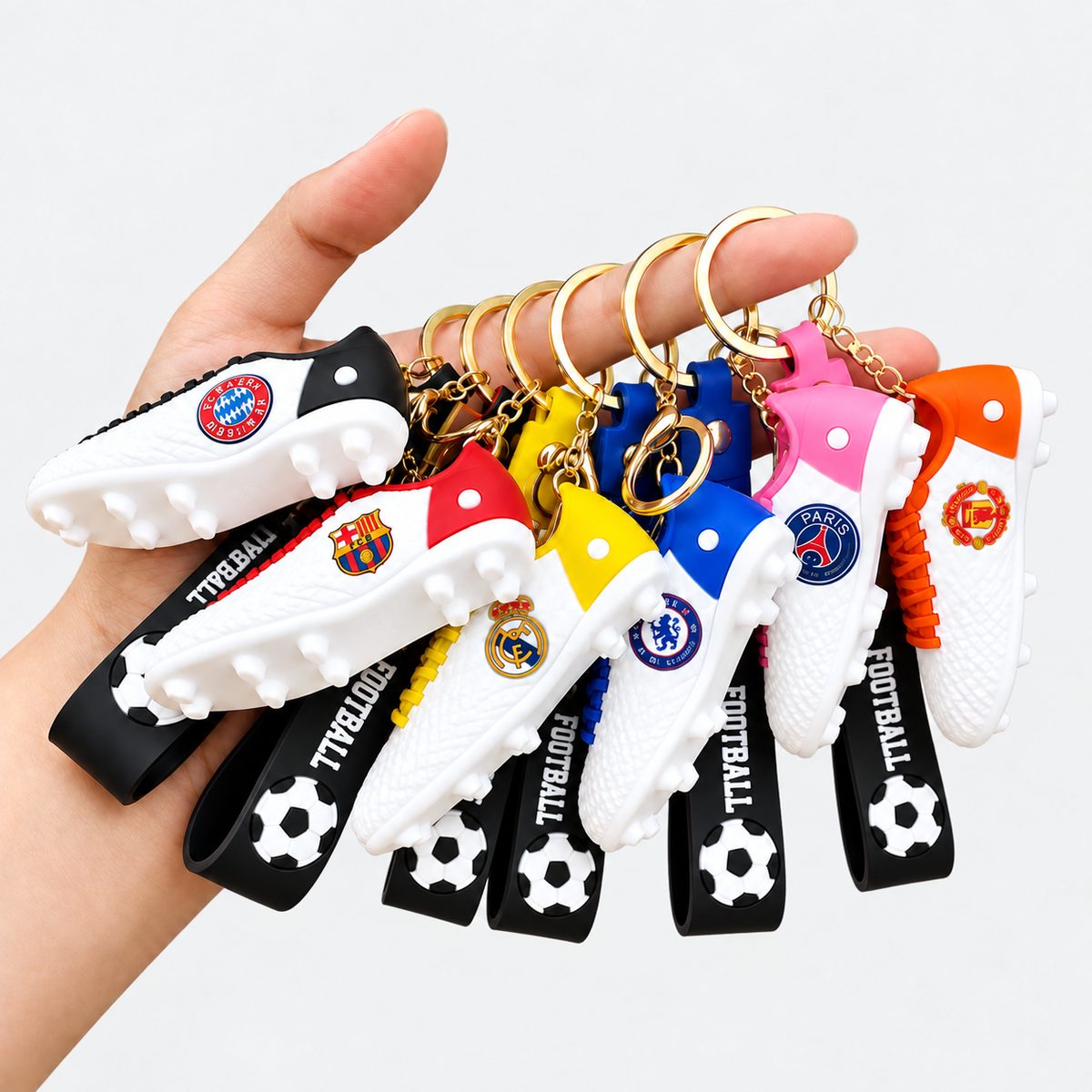 Hand holding football shoe keychains in assorted team colors