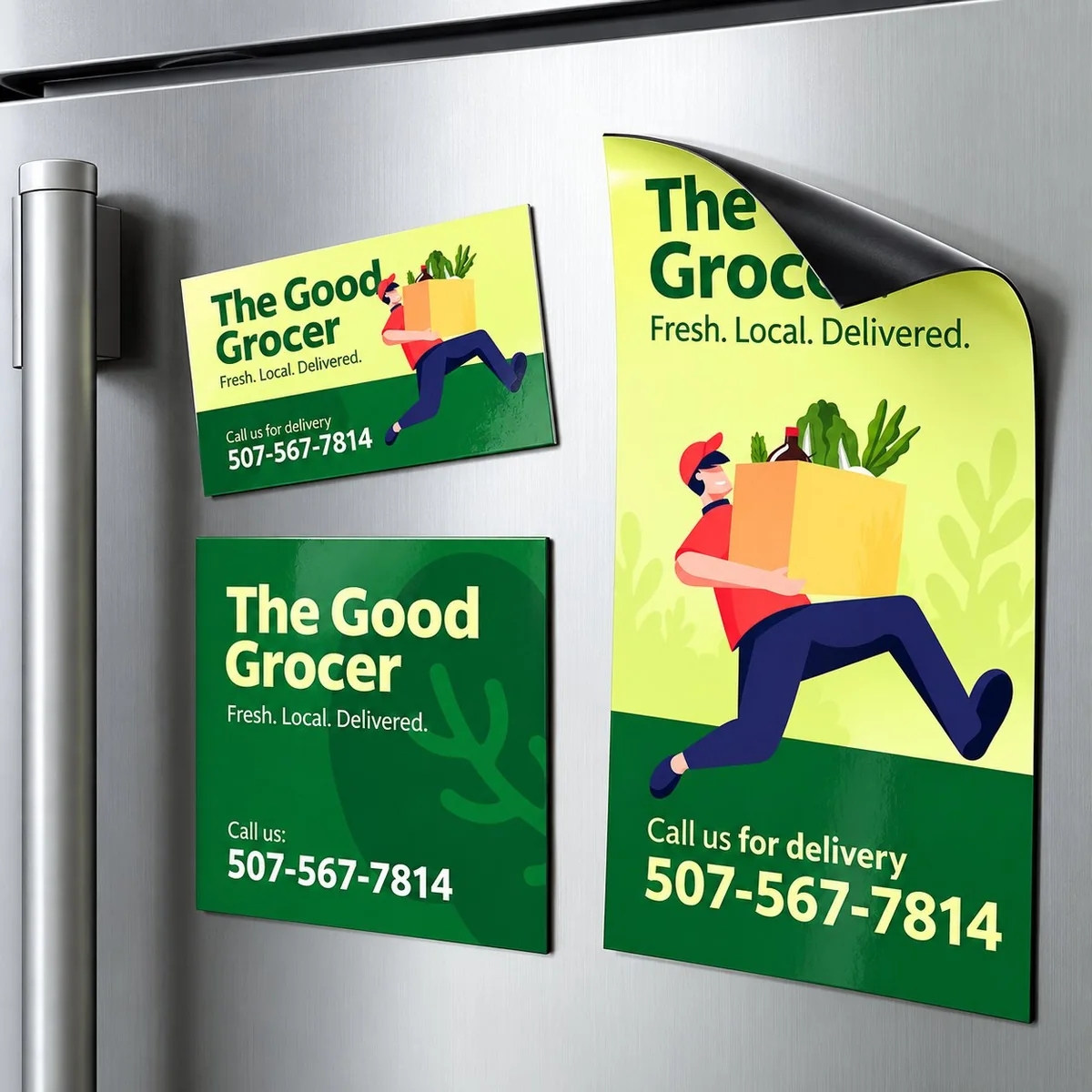 Three sizes of vinyl-style business magnets applied to a stainless steel fridge door