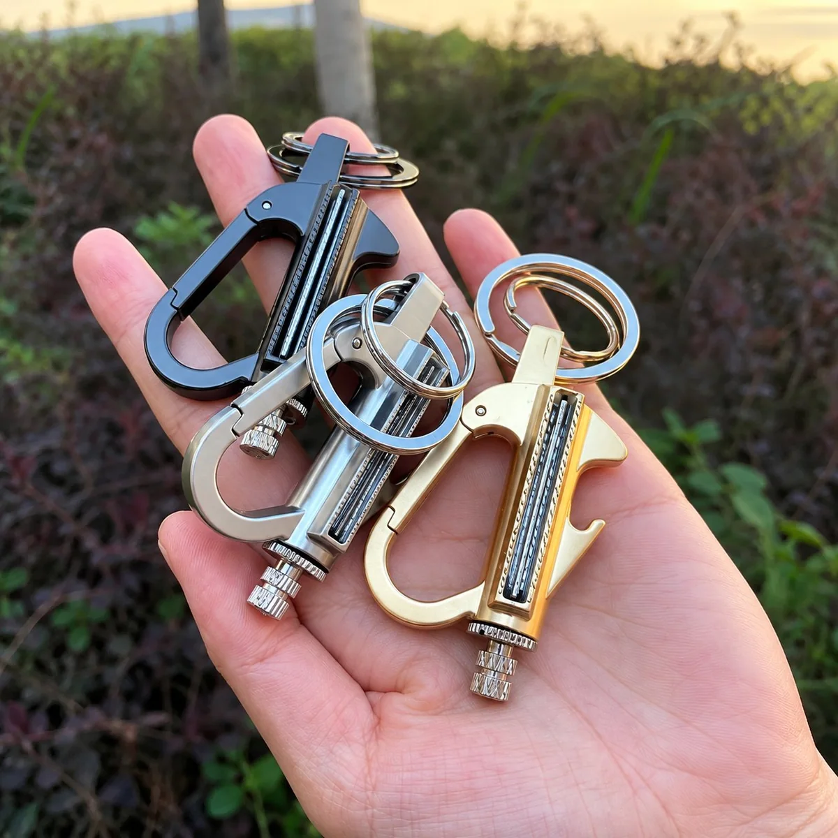 Open palm holding three metallic carabiner keychains in black