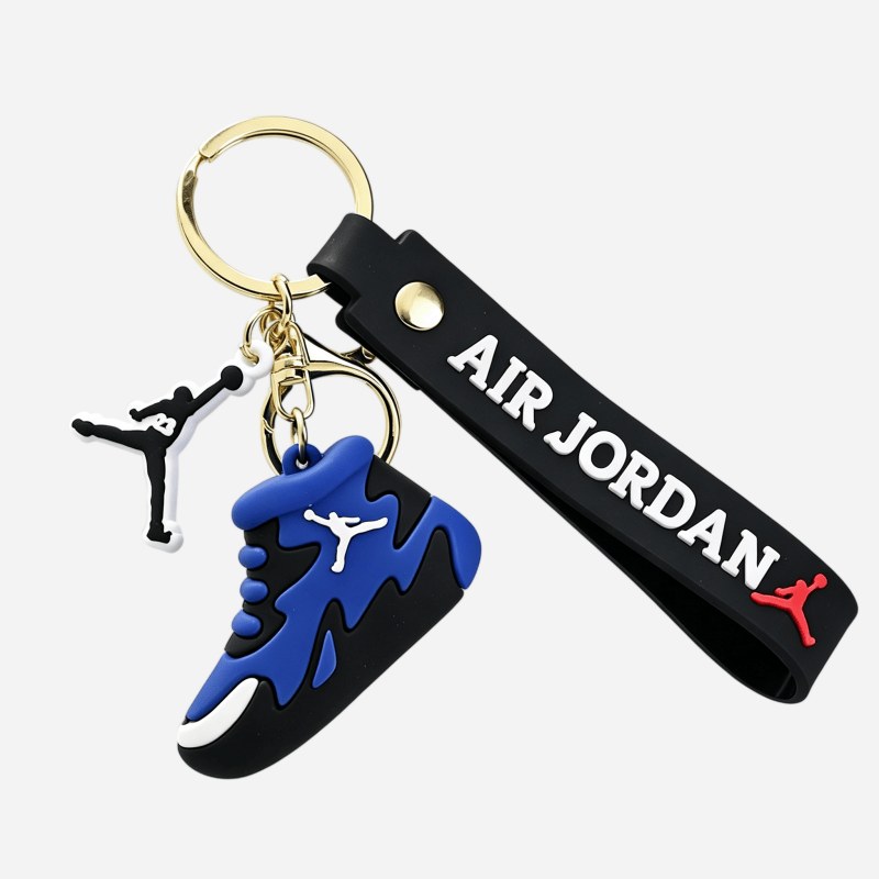 Jordan keychain in blue and black photographed side on, with the riveted silicone strap and the gold-tone charm
