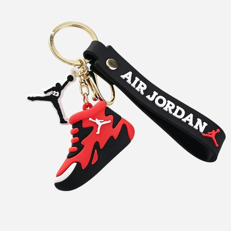 Jordan keychain in red and black with the riveted strap and the cast metal charm laid alongside the sneaker