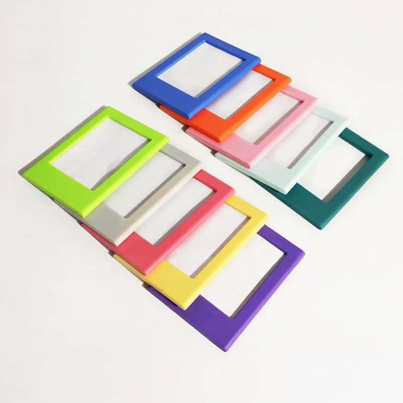 Magnetic picture frames in blue, orange, pink, white, green, red, yellow and purple fanned out on a white surface