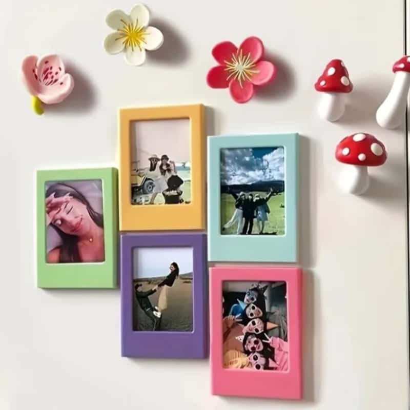Magnetic picture frames holding instant photos arranged across a white refrigerator door