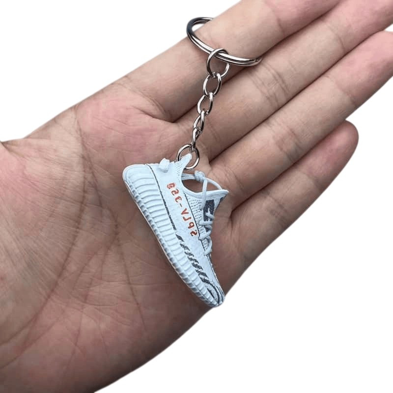 Yeezy shoe keychain in light blue PVC held by its split ring, showing the sole texture across 6.2 cm