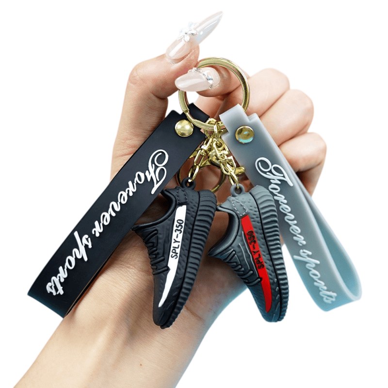 Yeezy shoe keychain tag straps printed with brand lettering, held in one hand