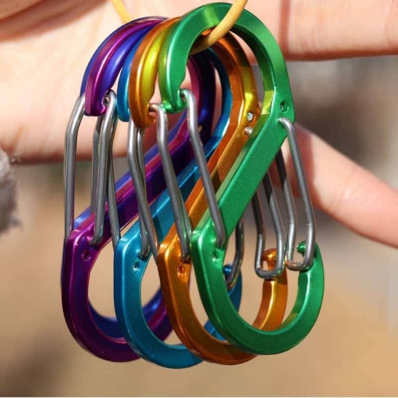 A handful of anodized aluminum carabiner keychains held outdoors
