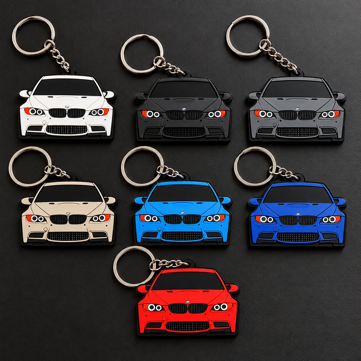Seven car-shaped soft PVC keychains modelled on a BMW front end, in white, black, grey, cream, light blue, blue and red, on a dark background