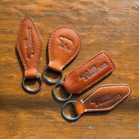 Brown leather keychains with stitched edges and debossed bear designs