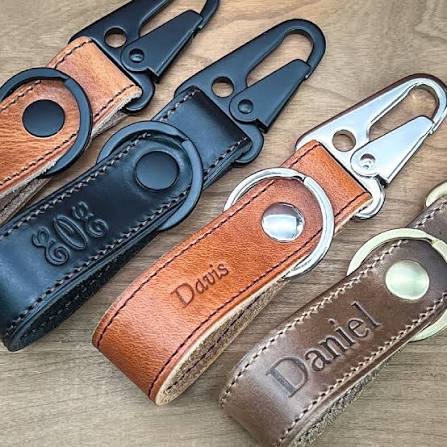 Close-up of personalized leather keychains with names and metal clips