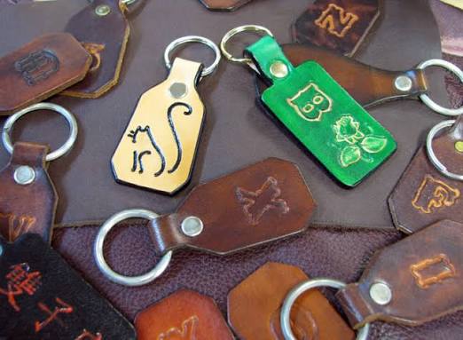 Assorted leather keychains in novelty tag shapes on a leather background