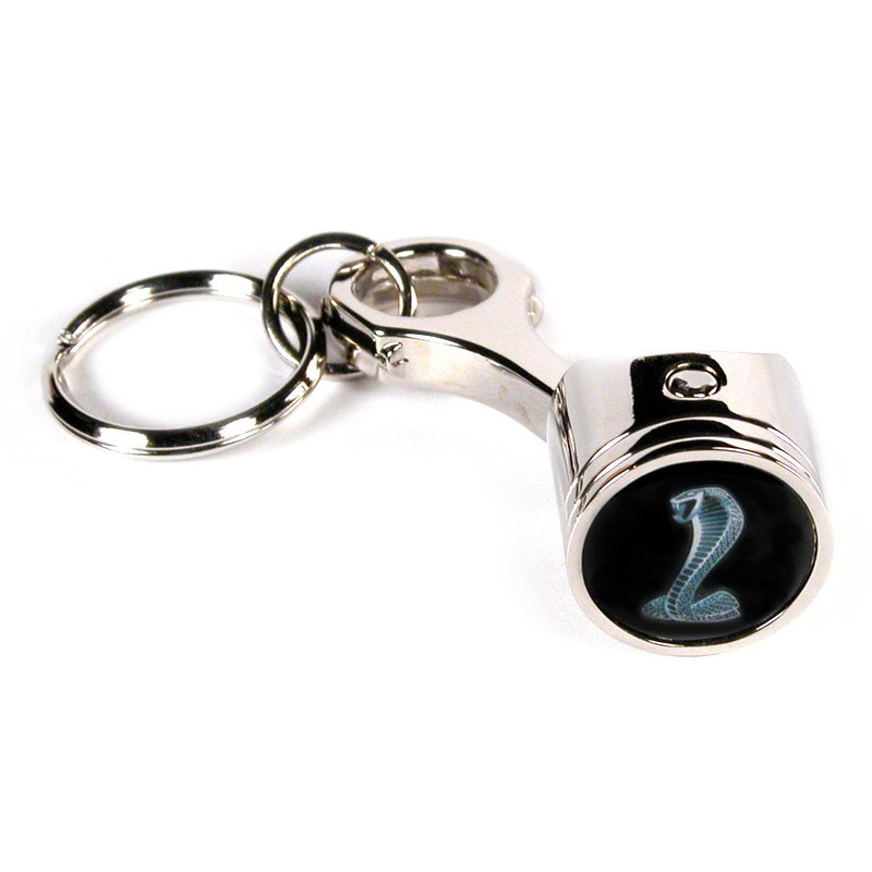 Chrome metal piston keychain with a silver cobra logo on a black epoxy face