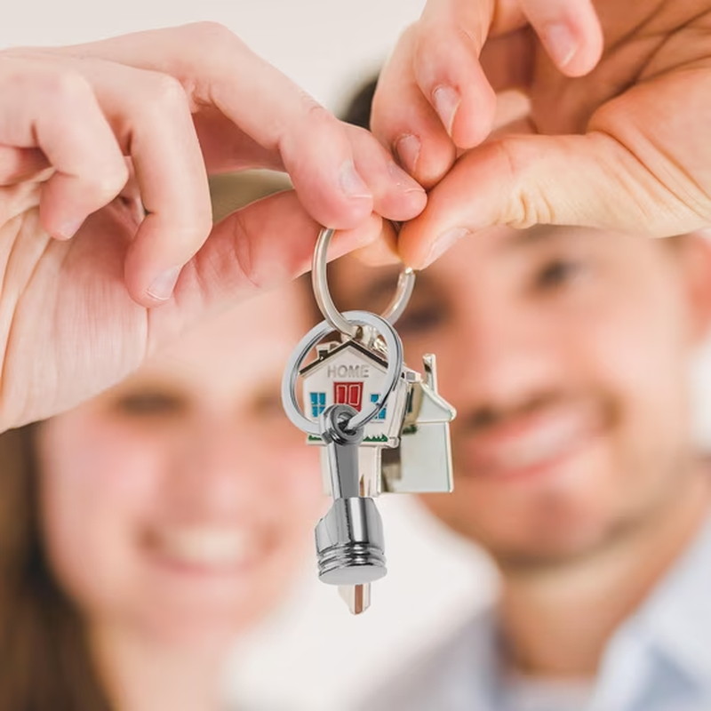 Hands holding a set of keys with a metal piston keychain attached as a keyring