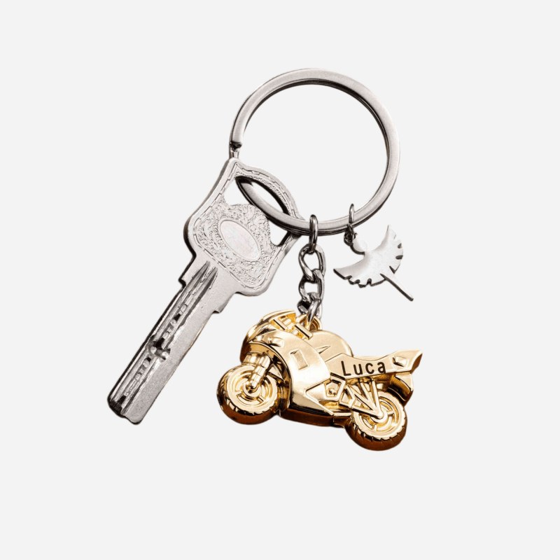 Gold motorcycle metal keychain on a key ring beside a house key